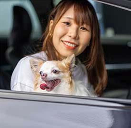 ペットを抱いて車に乗っている笑顔の女性イメージ